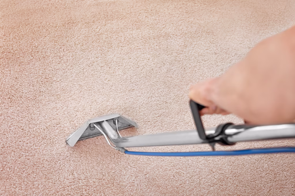 a professional carpet cleaning wand being held by an arm to clean a pink carpet